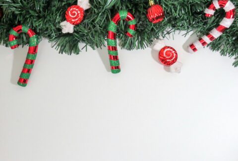 Christmas-themed image with candy canes and ornaments on greenery, perfect for holiday decorations.